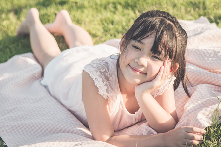 Beautiful asian girl lying on green grass,Vintage filterの写真素材