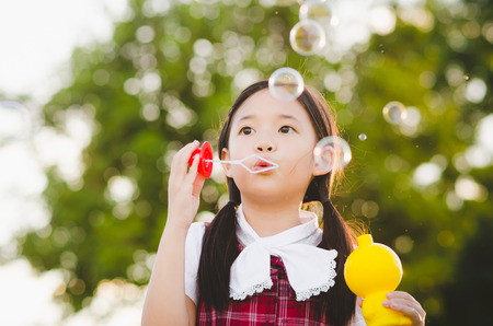 Cute asian girl is blowing a soap bubbles, Outdoor Portraitの写真素材