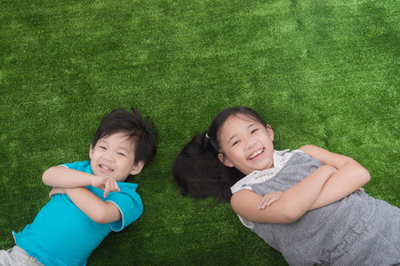 Cute asian child lying on green grassの写真素材