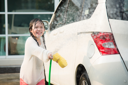 Beautiful asian child washing car in the gardenの写真素材