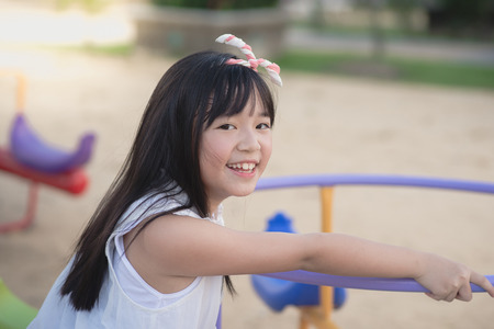 Little asian child having fun on carousel outdoorsの写真素材