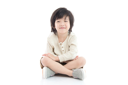 Happy asian boy sitting on white background isolatedの写真素材