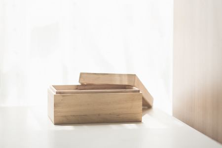 Open wooden box on white table under sunlight