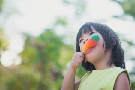 Cute Asian child eating an ice cream outdoorsの写真素材