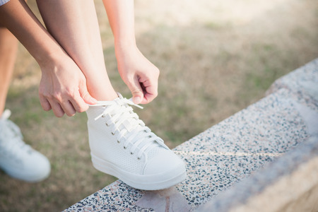 Asian woman tying laces in her white sneakersの写真素材