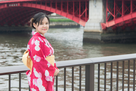 Asian woman wearing red kimono walking on a bridge,Tokyo japanの写真素材