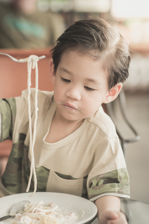Cute Asian chid eating Spaghetti Carbonara in restaurant,vintage fiterの写真素材