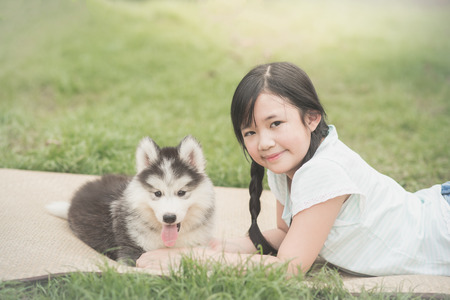 Beautiful asian girl playing with siberian husky puppy in the park,vintage filterの写真素材