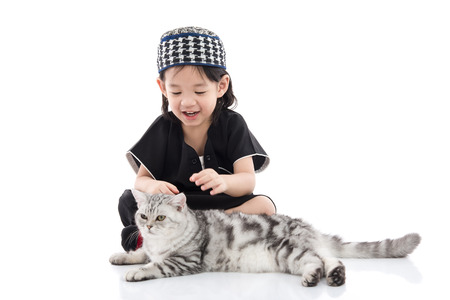 Cute muslim child playing with tabby cat on white background isolated.の写真素材
