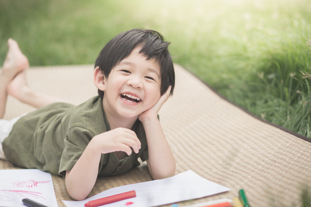 Cute Asian child drawing picture with crayon