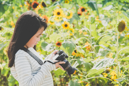 Beautiful Asian girl taking pictures on the sunflowers fieldの写真素材