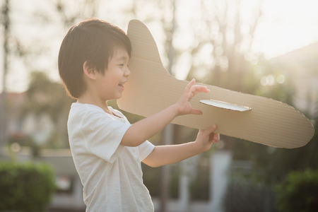 Cute Asian child playing cardboard airplane in thee park outdoorsの写真素材