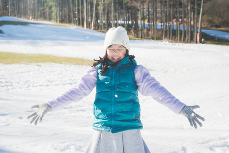 Happy asian girl smiling outdoors in snow on cold winter dayの写真素材