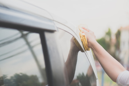 Asian woman washing car window with microfiber clothの写真素材