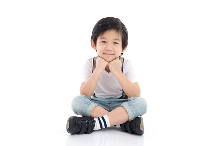Happy asian boy sitting on white background isolatedの写真素材