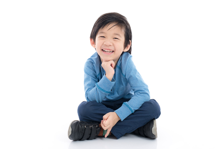 Happy asian boy sitting on white background isolatedの写真素材