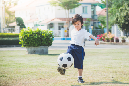 Asian boy kicking football on the fieldの写真素材