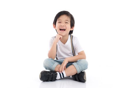 Happy asian boy sitting on white background isolatedの写真素材