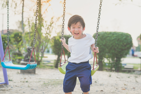 Cute Asian child playing on swing in the parkの写真素材