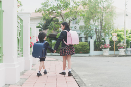 Cute Asian children  holding hand  together while  going to the schoolの写真素材