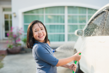 Asian girl washing car in the garden on summer dayの写真素材