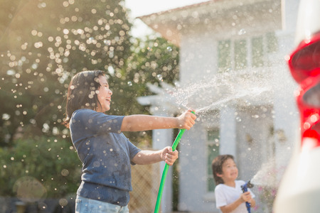 Asian children washing car in the garden on summer dayの写真素材