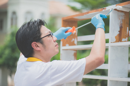Asian man paiting wooden shelf outdoorsの写真素材