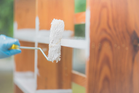Hand of man paiting wooden shelf outdoorsの写真素材