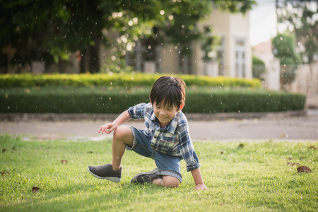 Cute Asian child playing in the park under the rainの写真素材