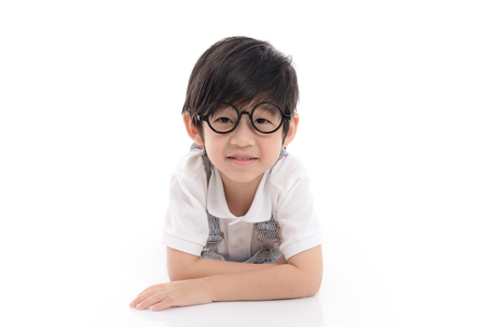Cute asian boy wearing glasses lying on white background isolatedの写真素材