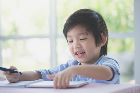 Cute Asian child drawing picture with crayonの写真素材