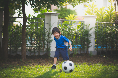 Asian boy kicking football in the parkの写真素材