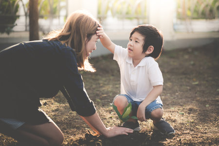 Asian mother and son planting young tree in black soil togetherの写真素材