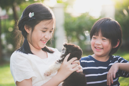Asian children playing with siberian husky puppy in the parkの写真素材