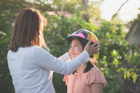 Asian mother wears a bicycle helmet to her daughterの写真素材