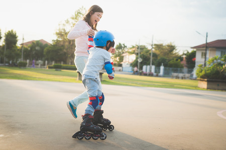 Asian mother helping her son to playing roller skate in the parkの写真素材