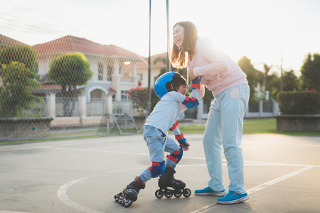 Asian mother helping her son to playing roller skate in the park