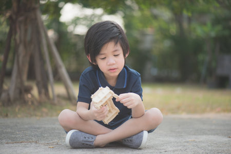 Cute Asian child playing wooden model car in the parkの写真素材