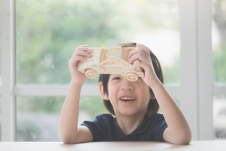 Cute Asian child playing wooden model car on a tableの写真素材