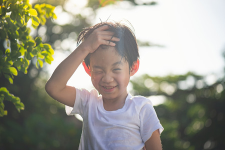 Cute asian boy has fun playing water in the garden
