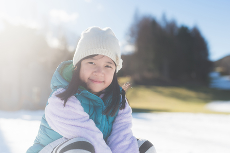 Happy asian girl smiling outdoors in snow on cold winter dayの写真素材