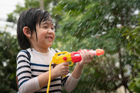 Cute Asian child playing with water gun in the summerの写真素材