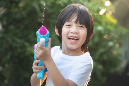 Cute Asian child playing with water gun in the summerの写真素材