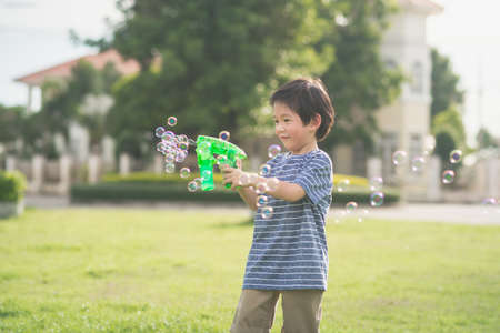 Cute Asian child Shooting Bubbles from Bubble Gun in the parkの写真素材