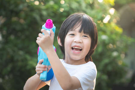 Cute Asian child playing with water gun in the summerの写真素材