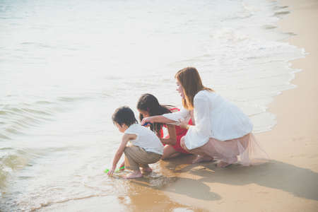Asian single mom playing with her children on the beachの写真素材