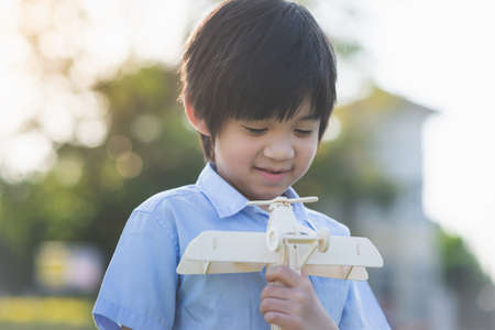 Cute Asian child playing wooden toy plane in the parkの写真素材