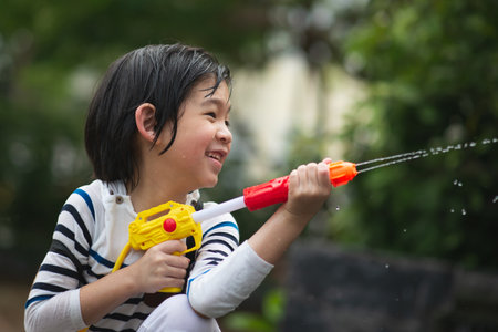 Cute Asian child playing with water gun in the summerの写真素材
