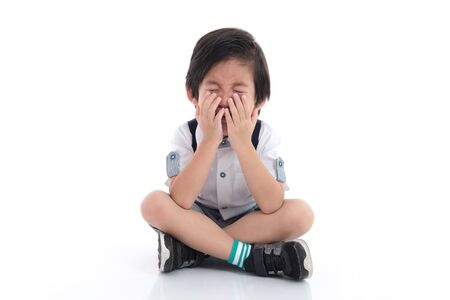 Close up of sad Asian boy sitting on white background isolatedの写真素材