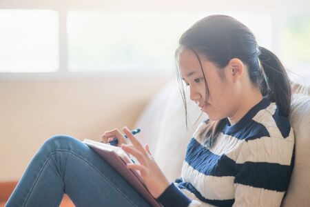 Asian girl drawing picture with digital pen on tablet pc computerの写真素材